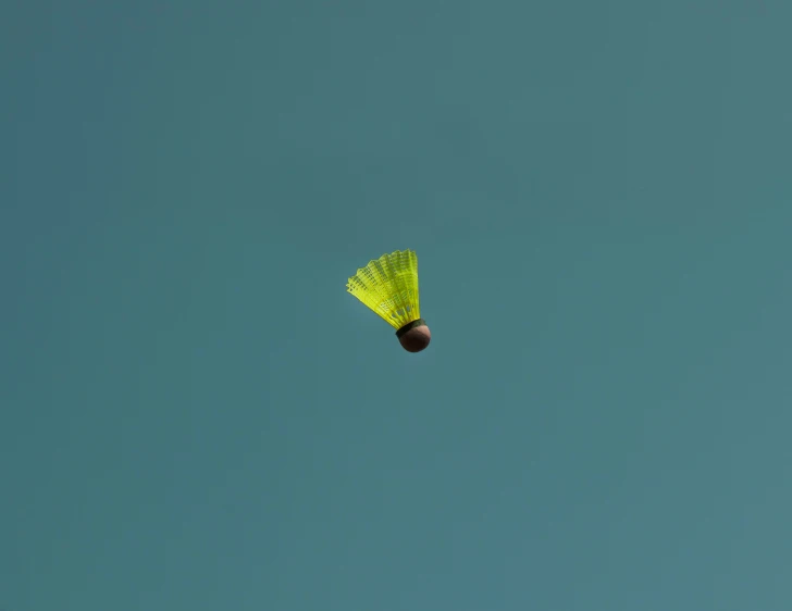 a green kite flying high in the sky