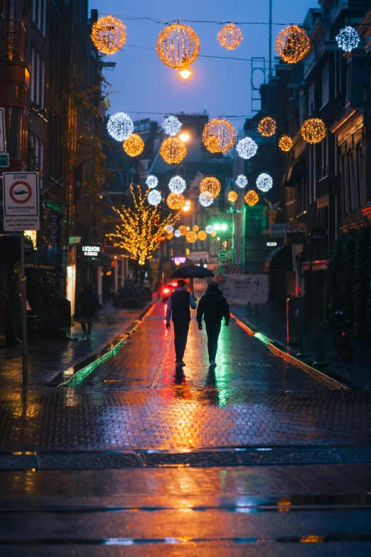 two people walking down the street during a rainy night