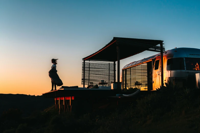 the silhouette of a person stands on a train platform