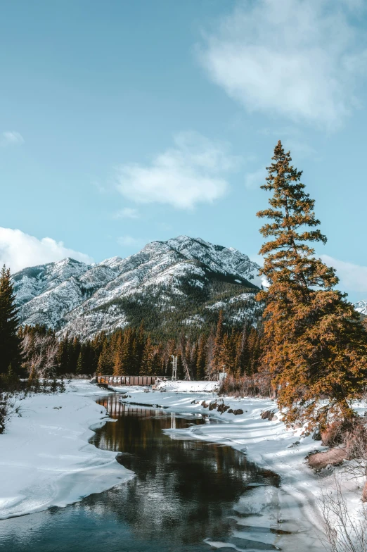 a stream in the snow with mountains in the background