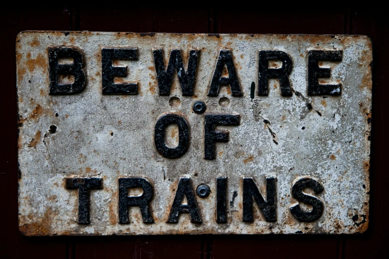 a rusted metal sign that says beware of trains