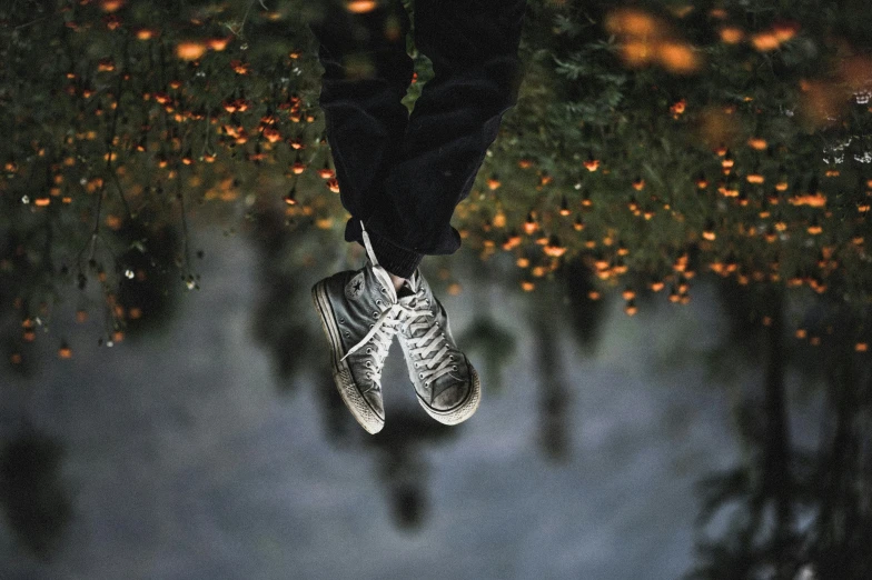 a person in black jacket and sneakers floating over water
