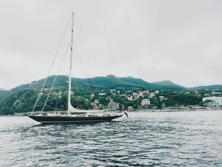 the sailboat is floating on the water near a city