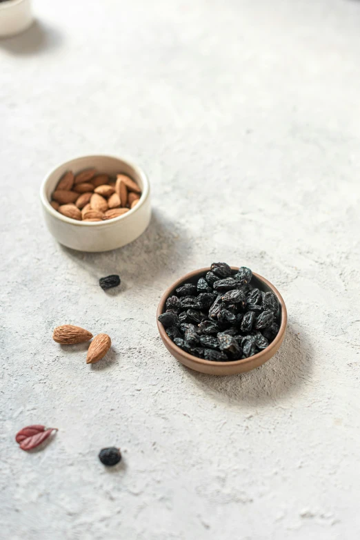 a bowl of nuts and two bowls filled with raisins