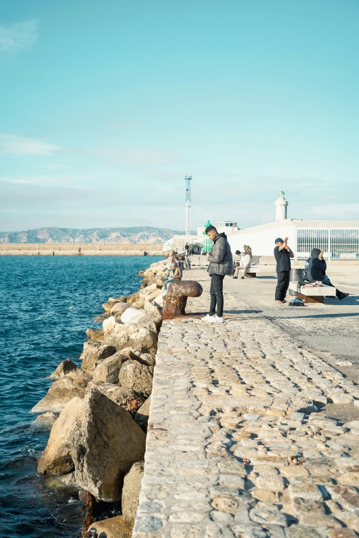 several people sitting on the wall by the water