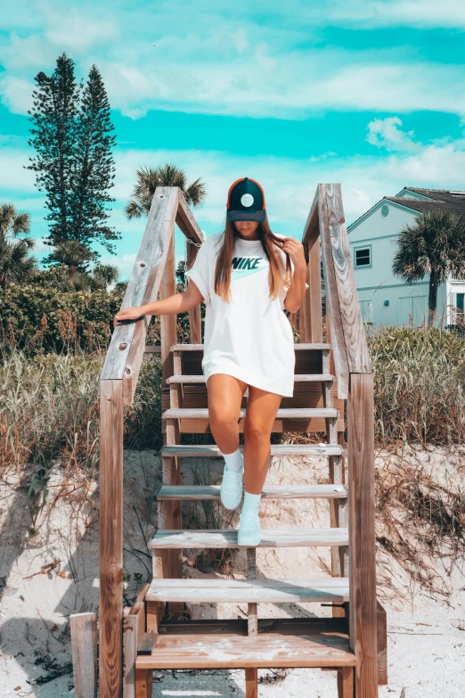 a woman poses on the steps to the beach