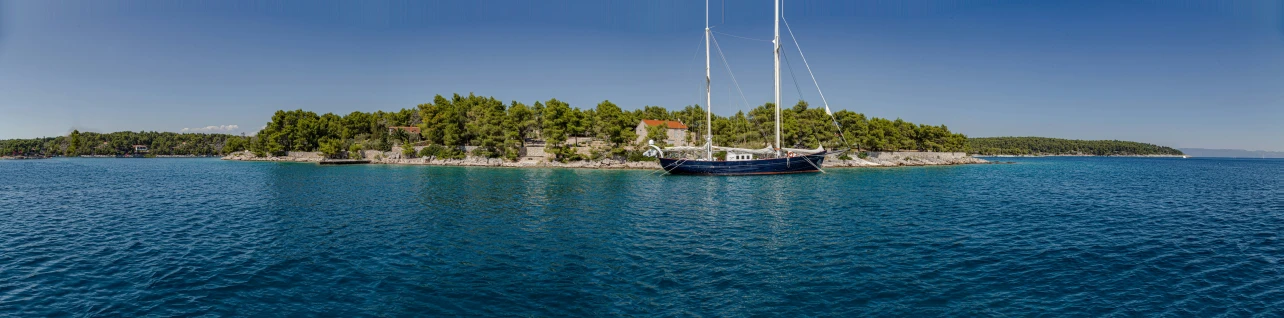 a boat on the water in front of a tree covered island