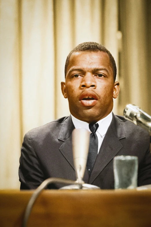 a man sits in front of a microphone at a conference