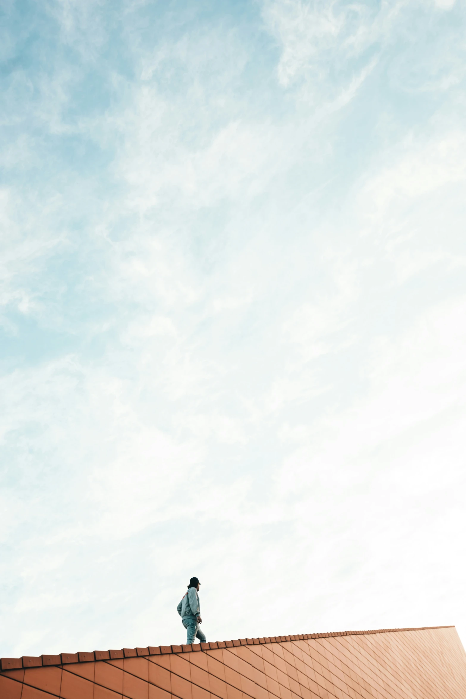 a lone man standing on top of the roof with blue skies