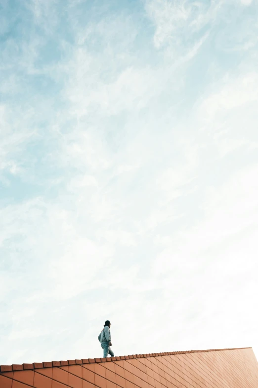 a lone man standing on top of the roof with blue skies