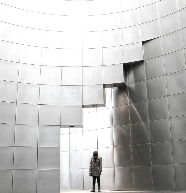 the man is standing outside looking into the silver building