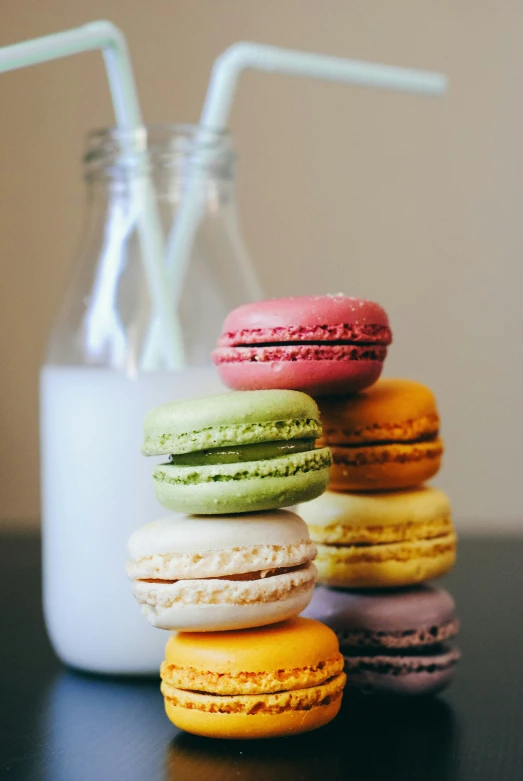 a bunch of small colorful donuts next to an empty glass