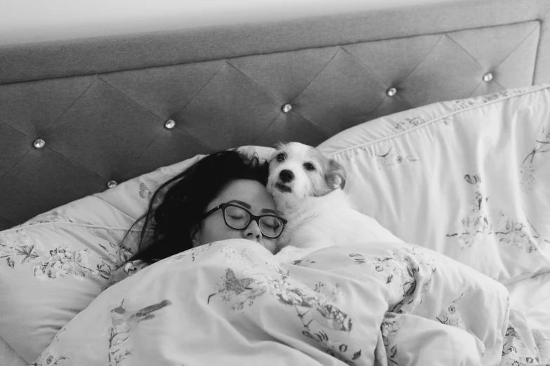 a woman laying in bed with a dog under a blanket