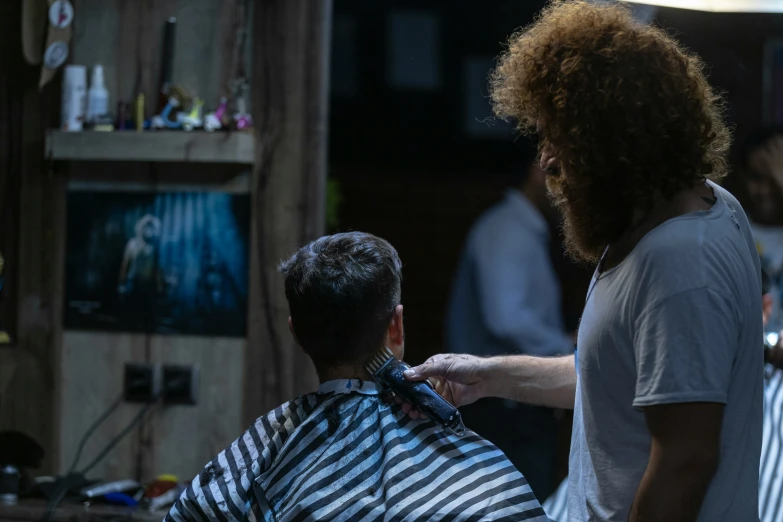 the hairdresser helps the barber cut his client's hair