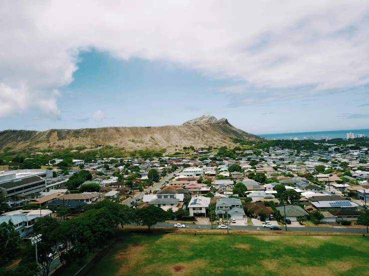 a small town nestled next to a large grassy area in front of a mountain