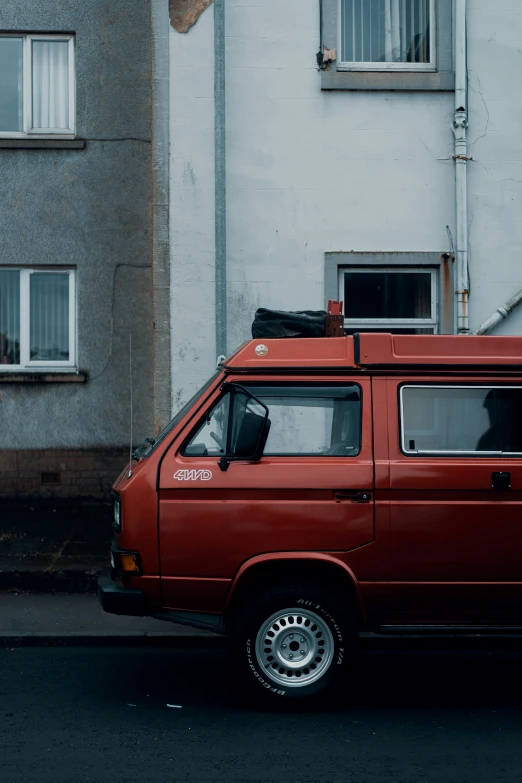 a red van with a black luggage box on top parked in front of a white building