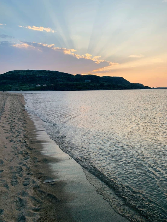 the beach is lined with footprints in the sand as the sun sets