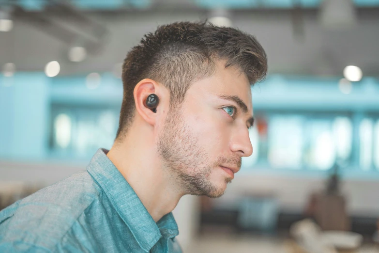 a man with blue eyes is wearing black ear buds