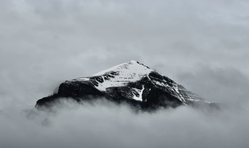 snow - covered mountain surrounded by thick clouds in the middle of winter