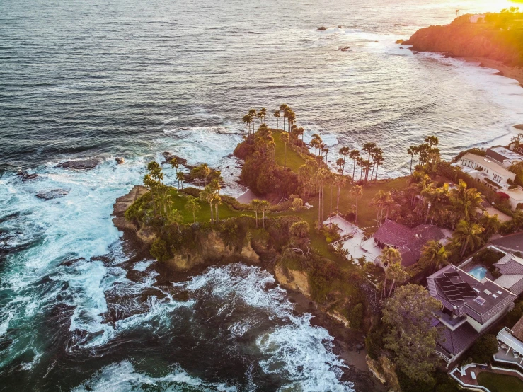 aerial view of a tropical coastline with a sunset behind the ocean