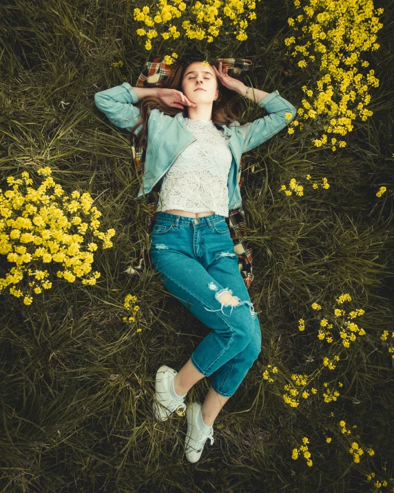 a woman laying on top of a field of flowers