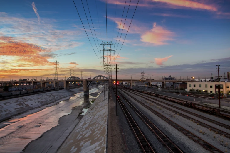 a train track at sunset with power lines above