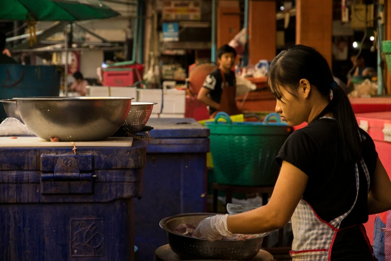 a young woman in an asian market putting food into a large bowl