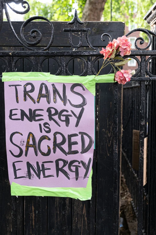 a piece of paper on the back of an iron gate with pink and green lettering