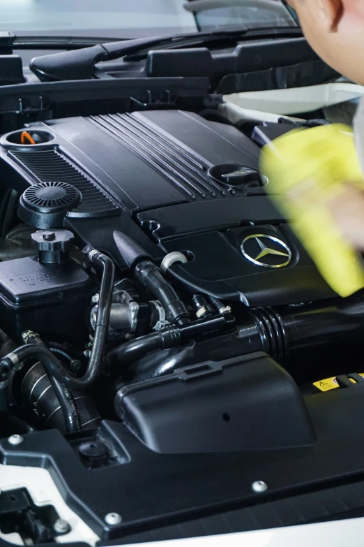 someone using sponge to clean a car engine