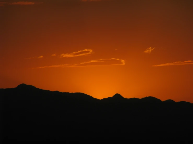 the sun sets behind a mountain range