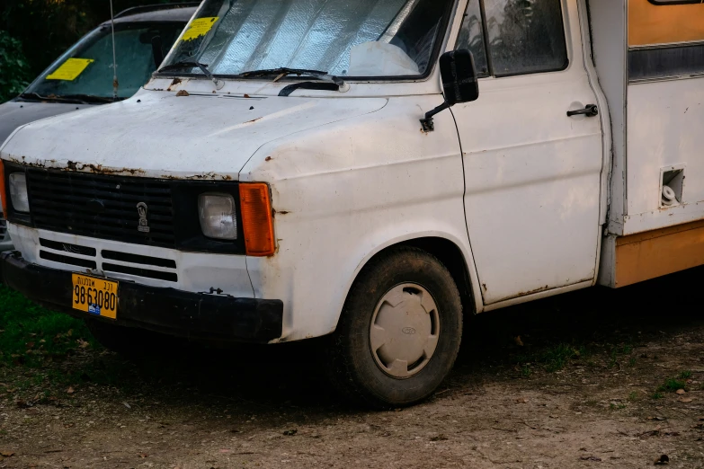 an old van is parked next to another one in the dirt