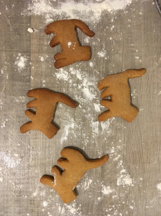 four cookie cutters shaped like hand and foot on floured surface