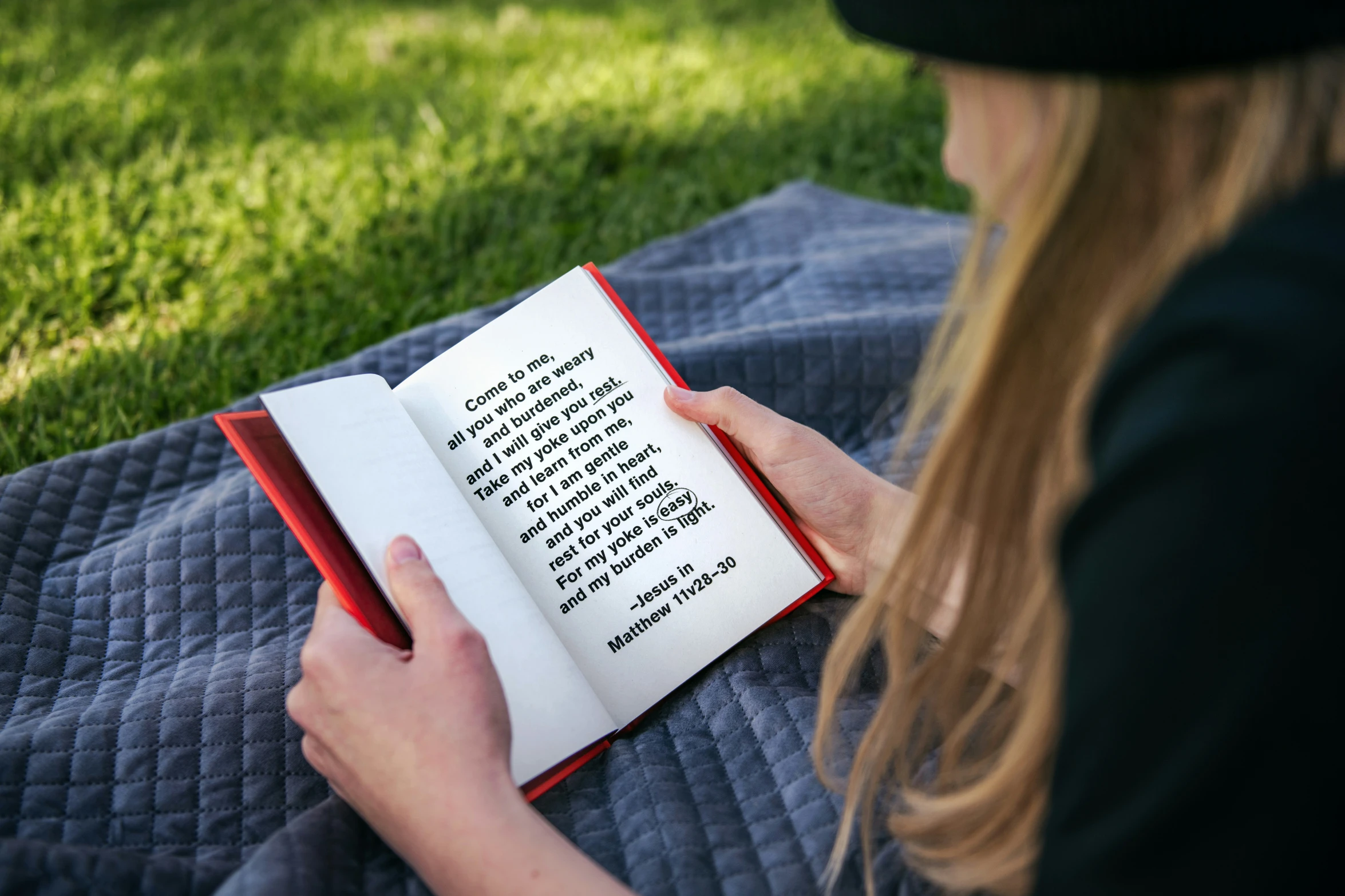 a woman is reading a book while laying on a blanket