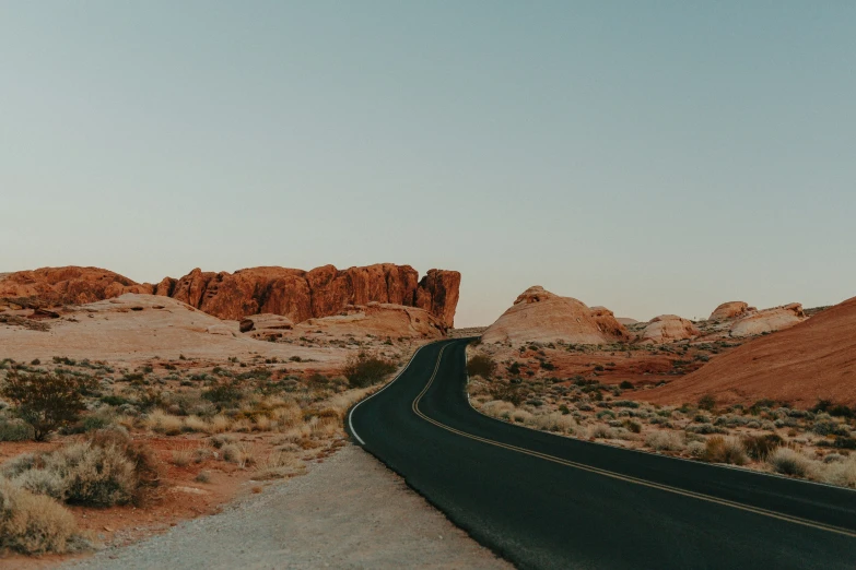 a deserted desert road with large rock formations