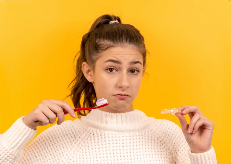 a girl brushes her teeth with a toothbrush in her hand