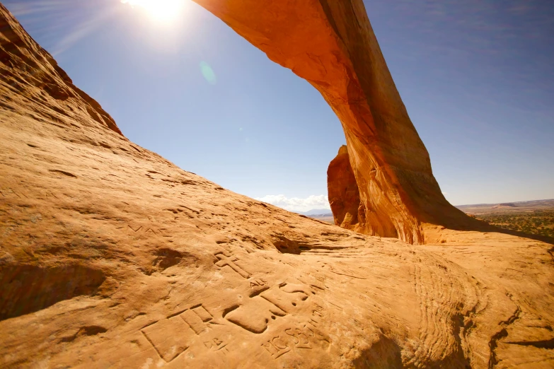 an arch over a sandy hill with the sun setting