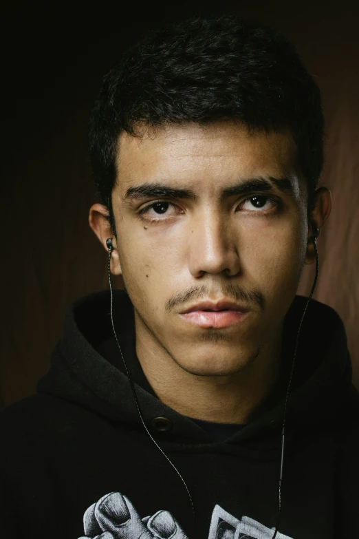 a young man wearing ear buds and a black hoodie