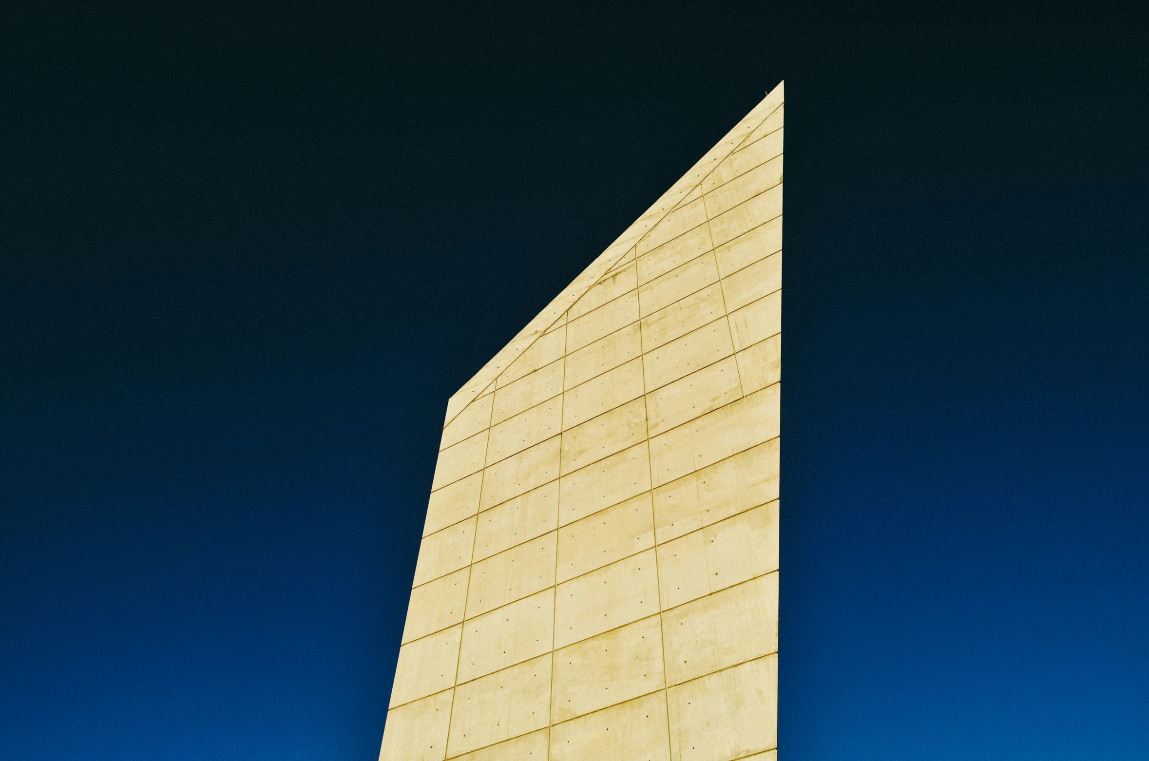 the side of a very tall concrete structure in the daytime