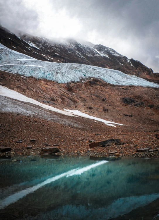 snow covered mountains on the side of a lake