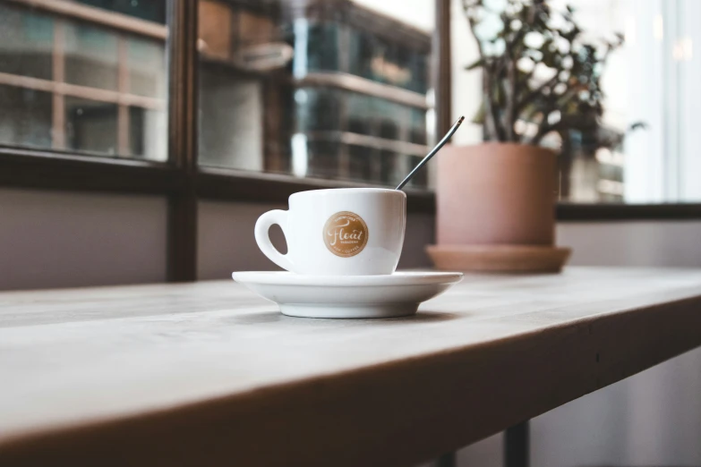 the cup and saucer on the table have two spoons in them