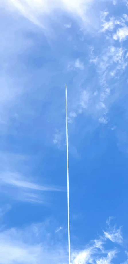 a large jet flying through a blue cloudy sky
