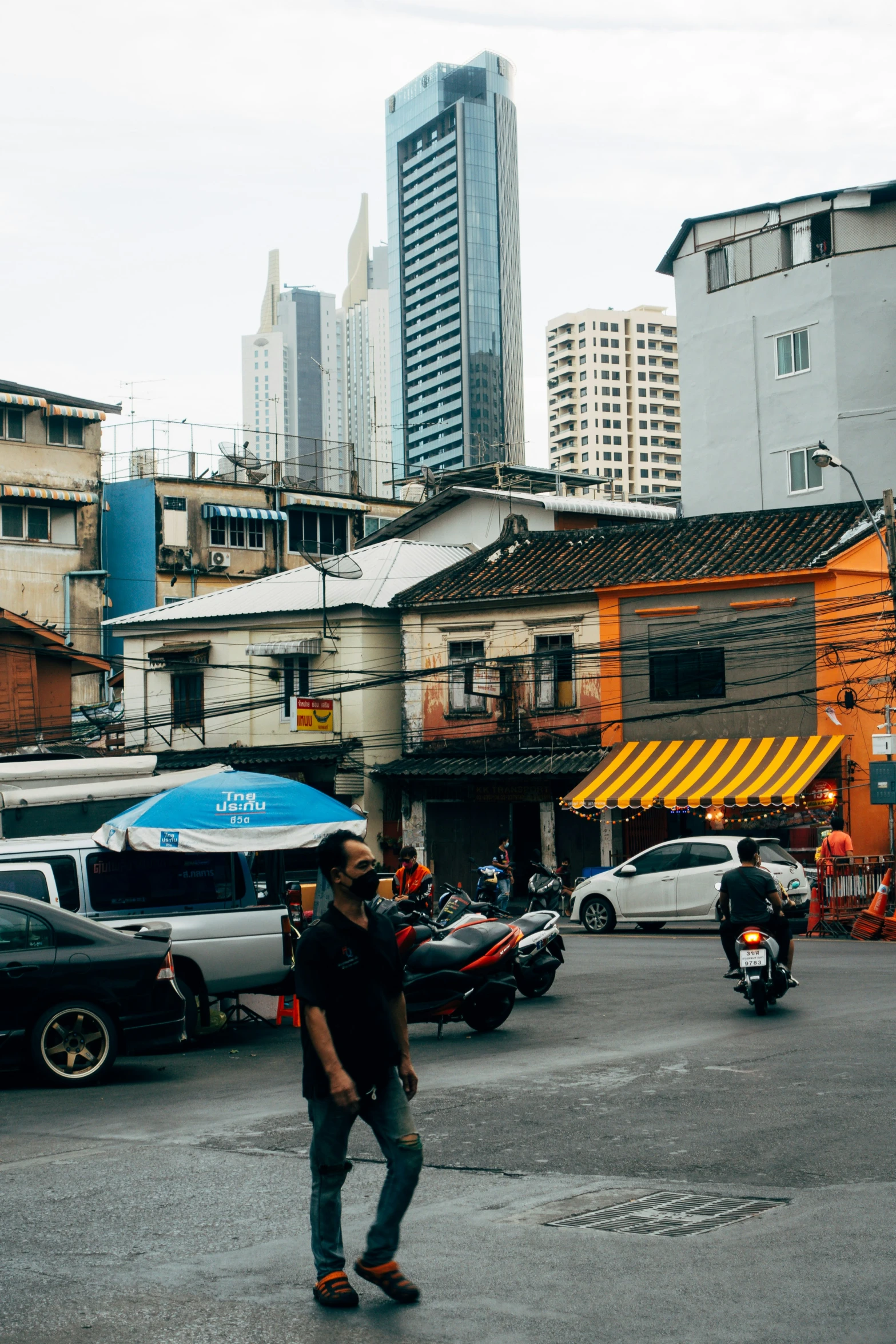 an asian man standing on the street next to some vehicles