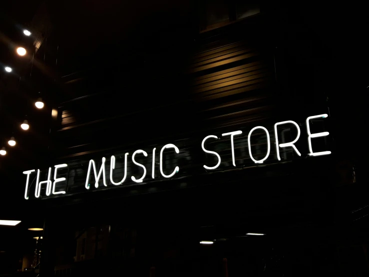 the sign for the music store that is lit up at night