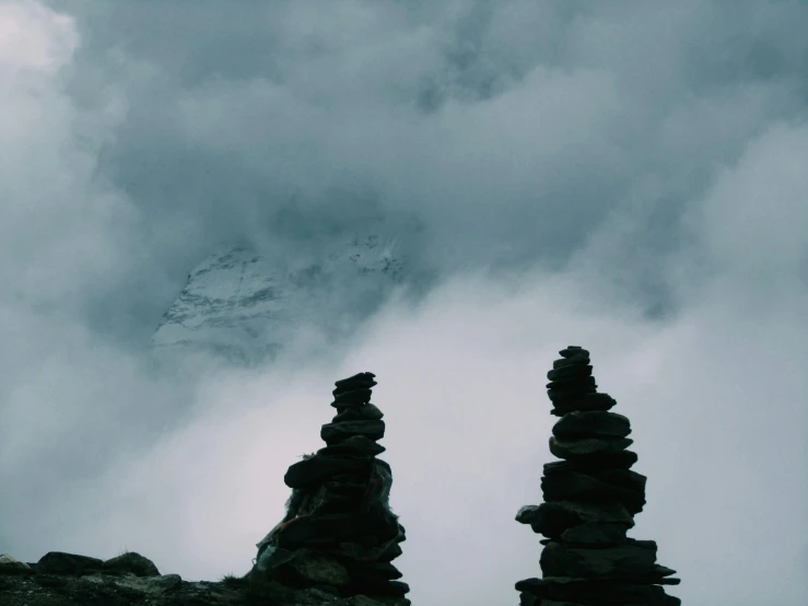 rocks in front of a mountain with a sky filled with clouds