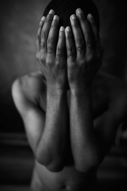 black and white image of man covering his face with hands