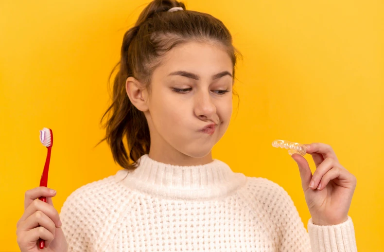 a girl is holding soing to her mouth