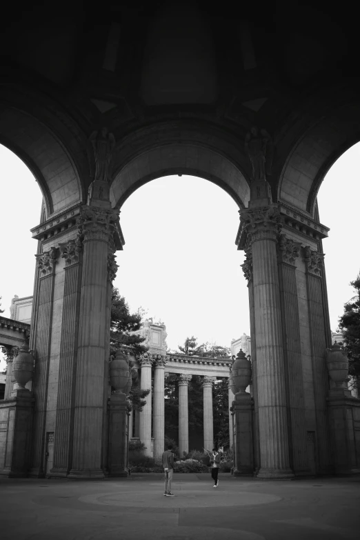 a couple is standing under an archway that has columns