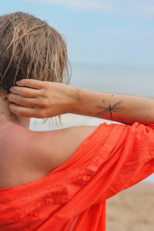 the back of a woman with a cross tattoo on her arm