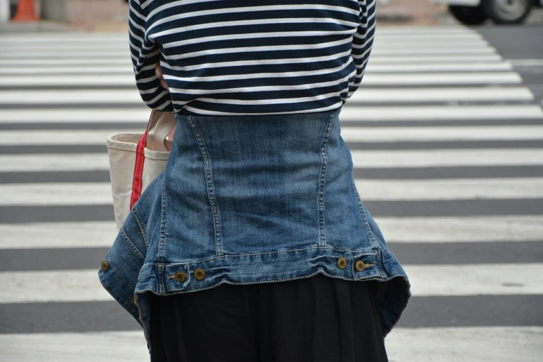 there is a woman that is standing on the street holding a purse