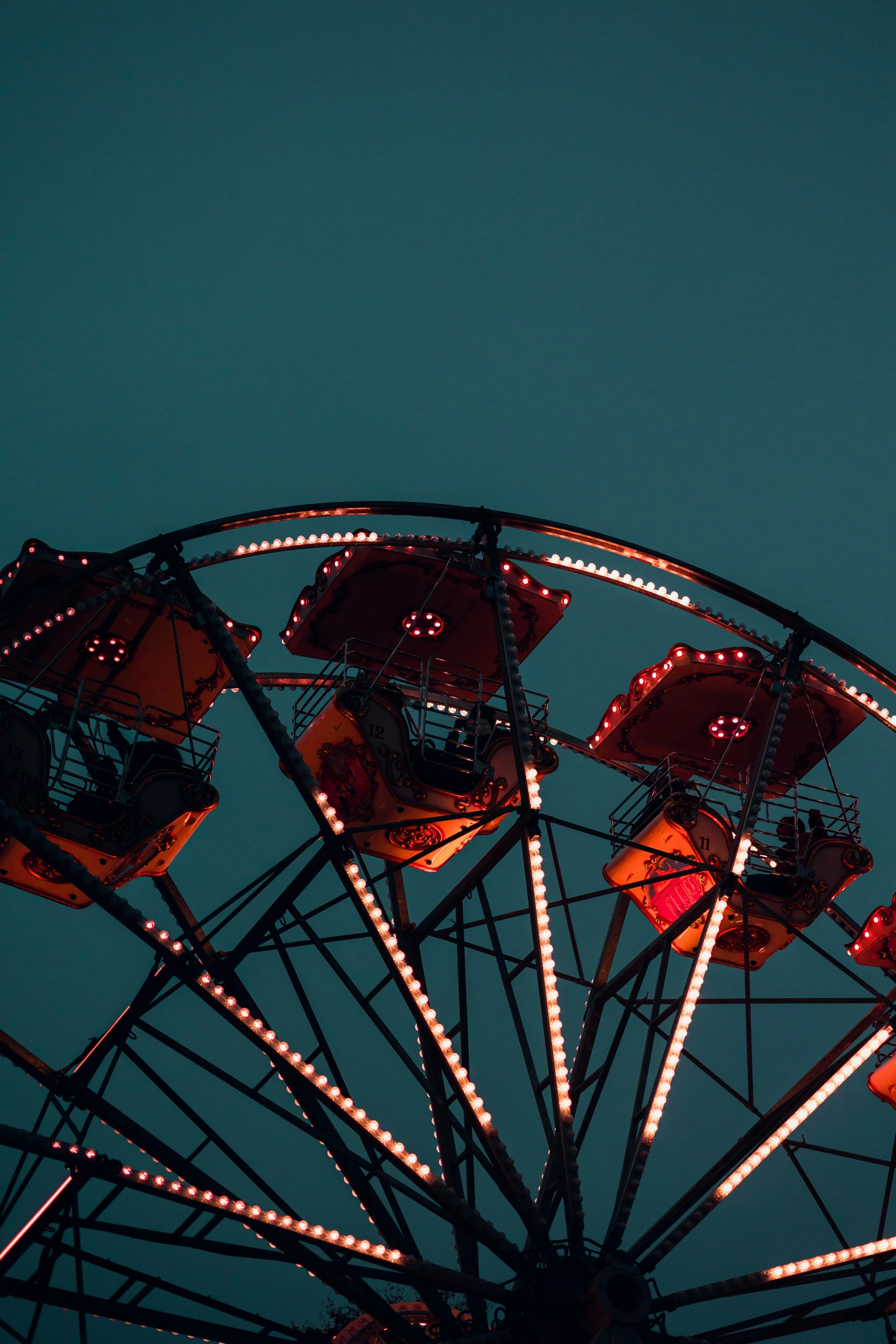 a carnival ferris wheel and light displays against a blue sky